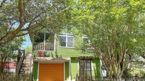 Una casa de dos pisos con fachada verde, cerca de madera y garaje.