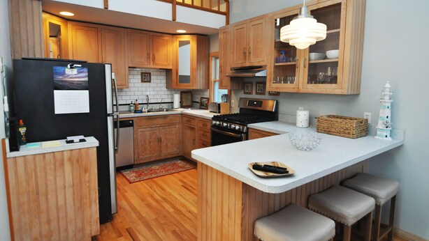 Una cocina moderna con armarios de madera, una isla central y una lámpara colgante.