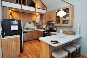 A modern kitchen with wooden cabinets, a central island, and a hanging light fixture.