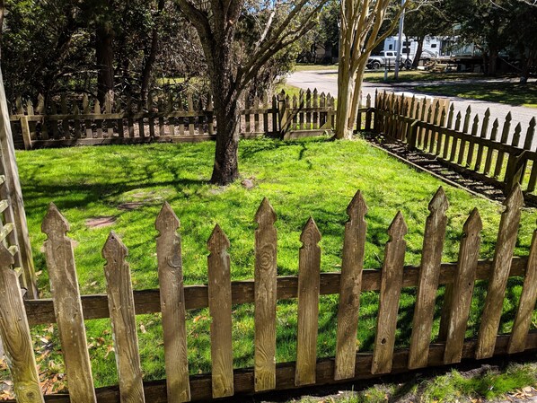 A fenced yard with a grassy area and trees. - Havana Cabana; Pet Friendly and family friendly home (Ocracoke)