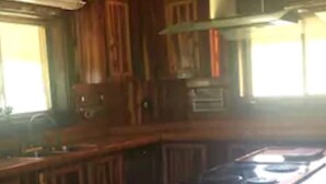 A wooden kitchen with a central island, cabinets, and a range hood. - LOG HOME CANINE RETREAT (Pyatt)
