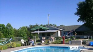 A swimming pool with a tiled deck, a covered seating area, and a flagpole with an American flag. - Wolf Creek Farm ~ For a 'Howling' Good Time! (Ararat)
