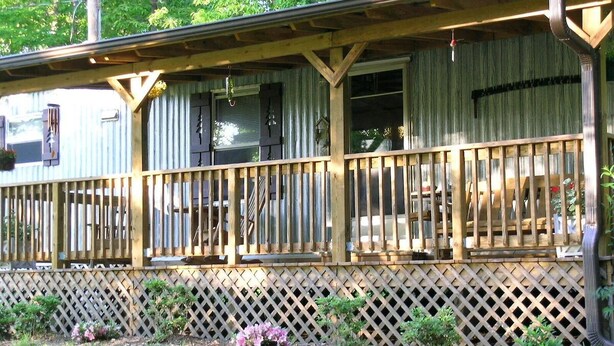A wooden cabin with a covered porch and lattice fence. - Wolf Creek Farm ~ For a 'Howling' Good Time! (Ararat)