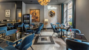 Un restaurante moderno con sillas azules, mesas negras y una araña.