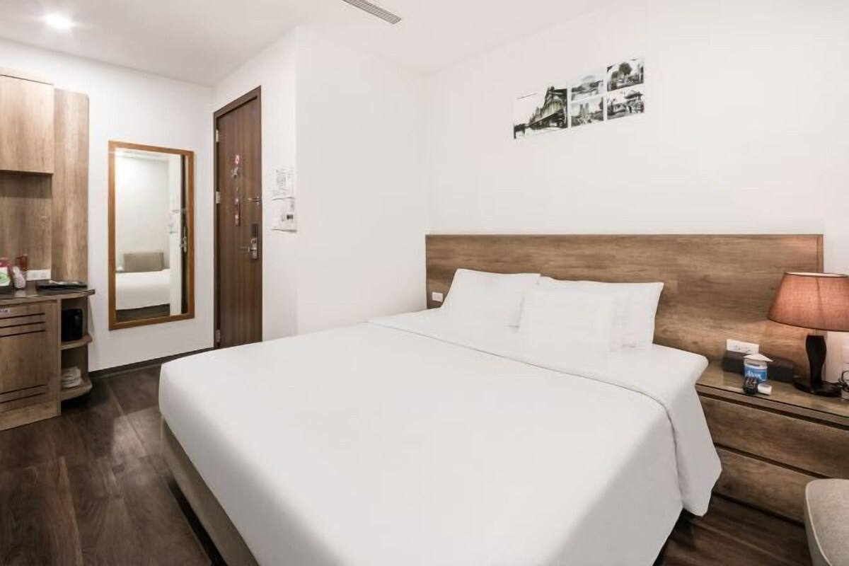 Ein Hotelzimmer mit einem großen Bett, einem Holz-Kopfteil, einem Nachttisch mit Lampe, einem Kleiderschrank und einem Spiegel.