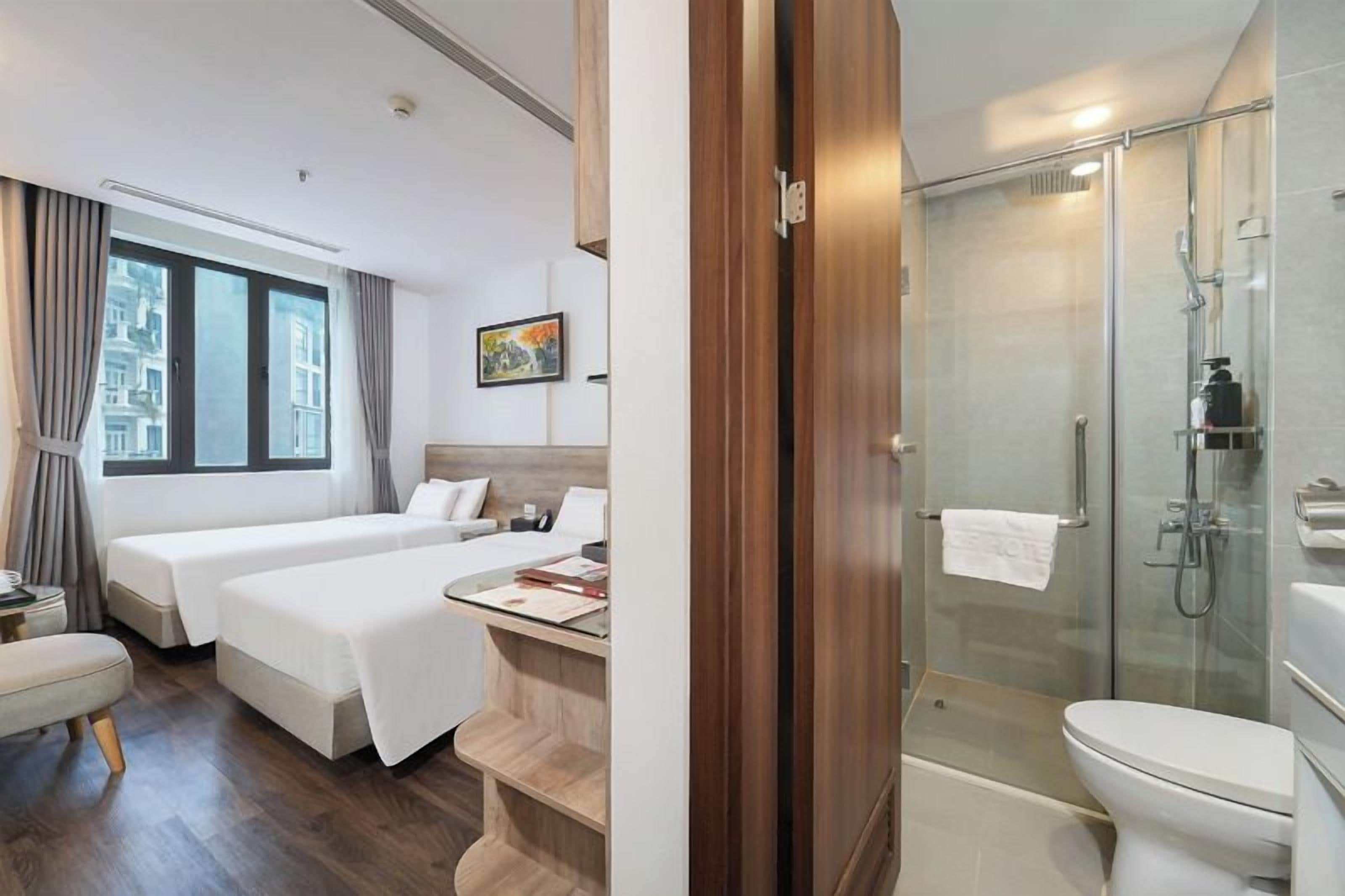 Habitación de hotel con dos camas, ducha y baño.