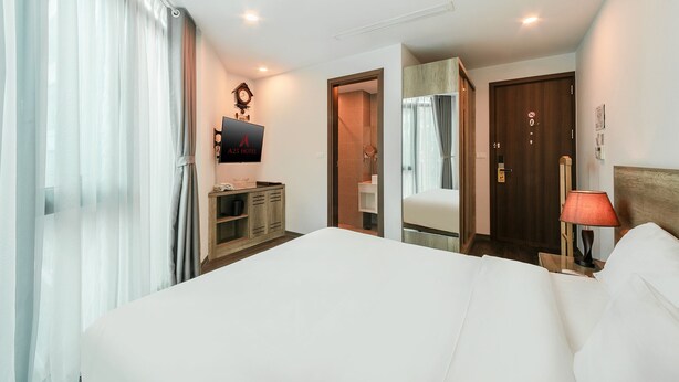 A hotel room with a large bed, a wooden dresser, a mirror, a clock, and a door with a sign. - A25 Hotel - Hoang Dao Thuy 1 (Hanoi)