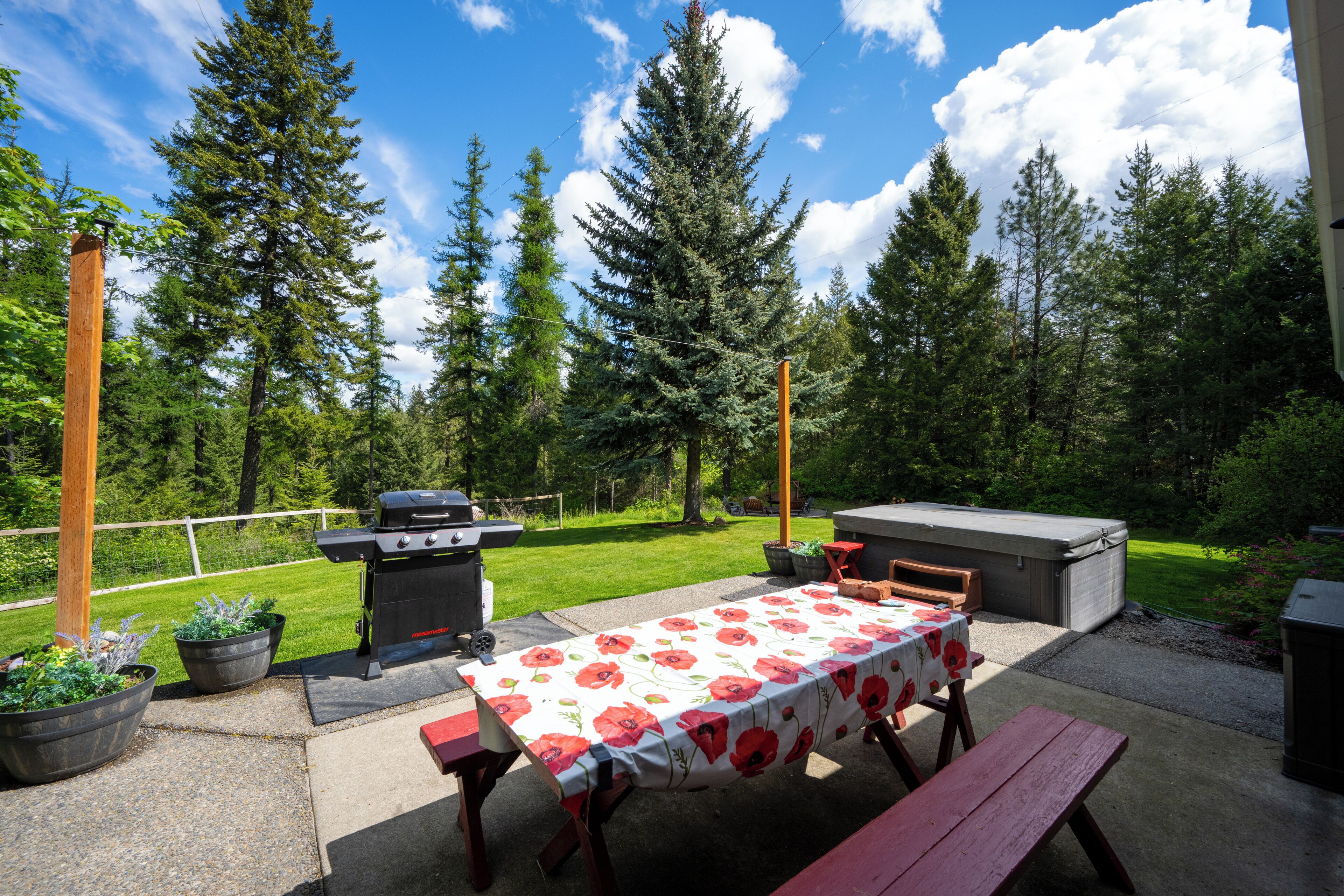 An outdoor patio with a table set for dining, a grill, and a hot tub.