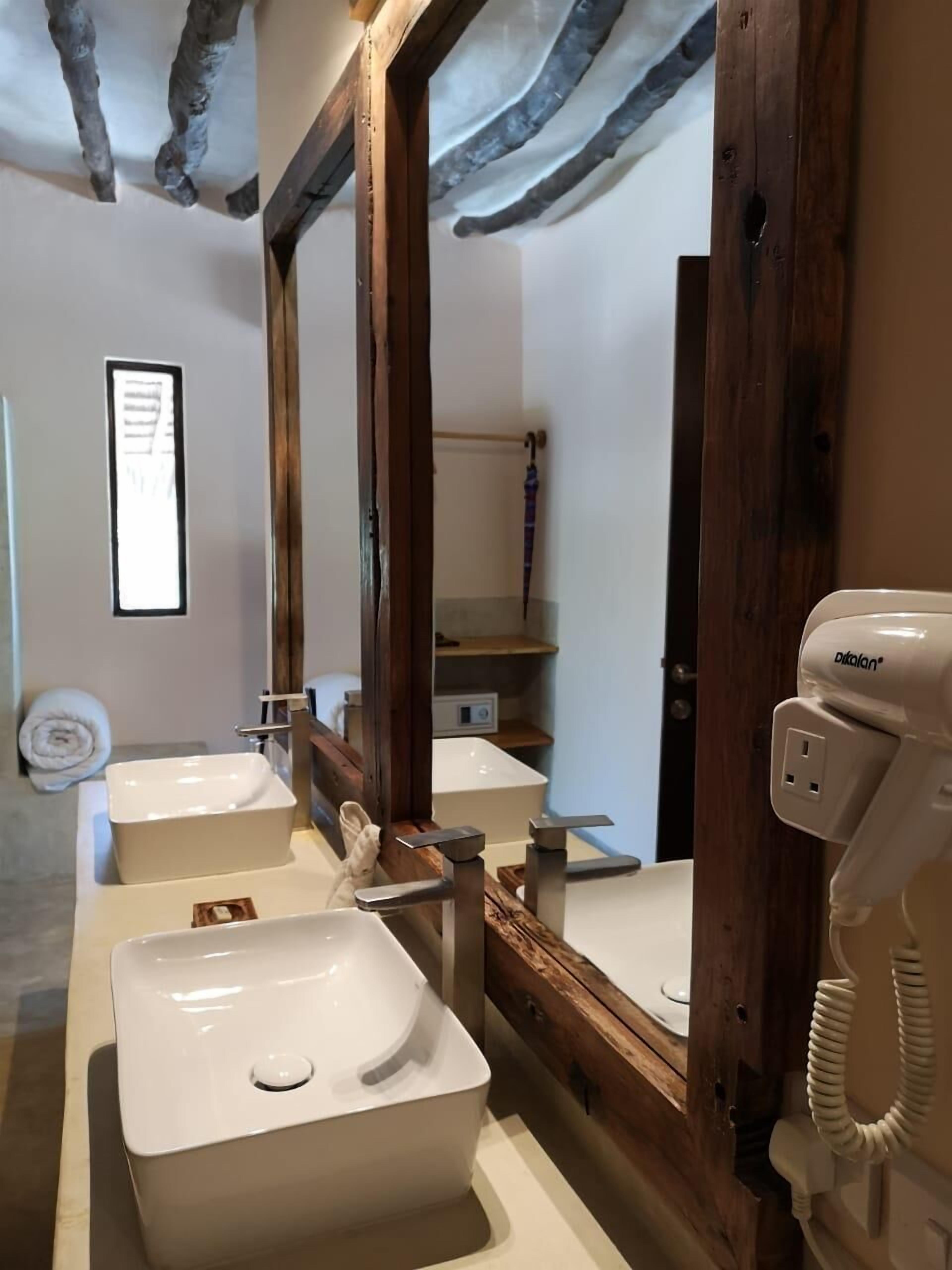 Une salle de bain avec trois lavabos, un grand miroir et un sèche-cheveux.