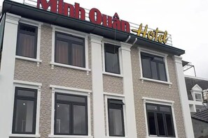 A hotel named Minh Quan with a modern facade, multiple windows, and a prominent sign.