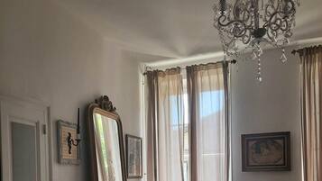 Une chambre à coucher avec un grand lit, une commode, un miroir et un lustre.