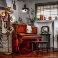 Una habitación con un piano de madera, un radiador y una ventana que ofrece vistas al exterior.