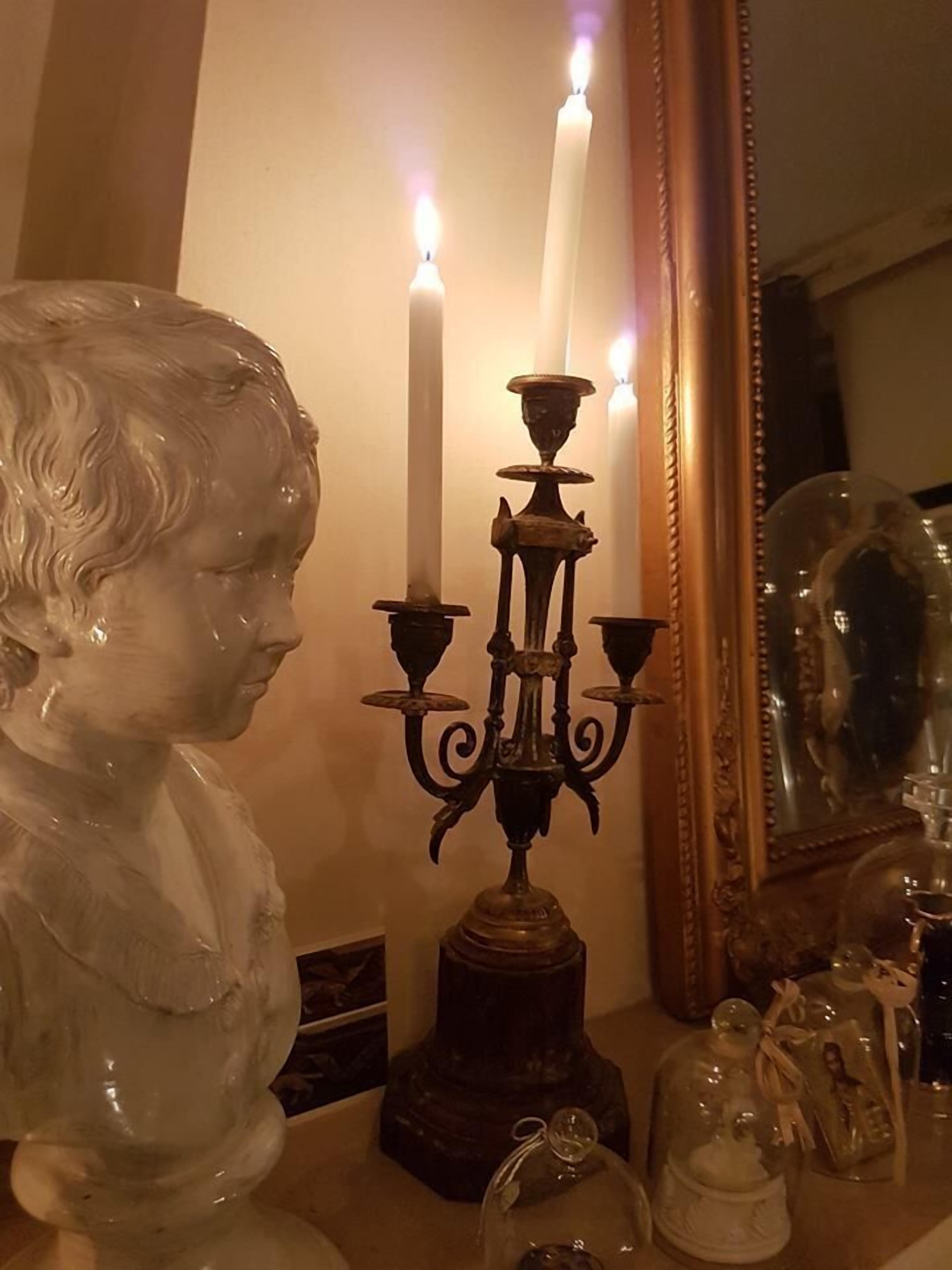 A room with a bust sculpture, a candelabra, and a mirror.