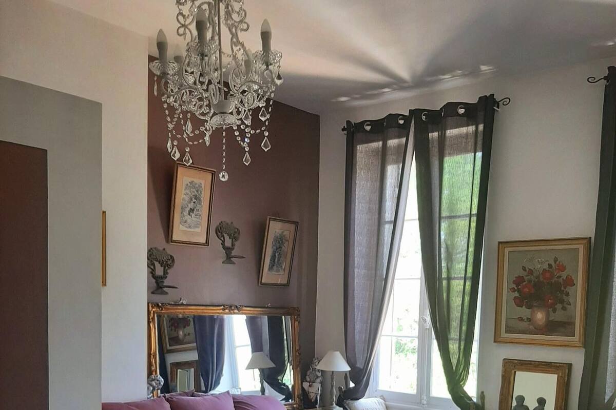 A bedroom with a large bed, a chandelier, a dresser, and a mirror.