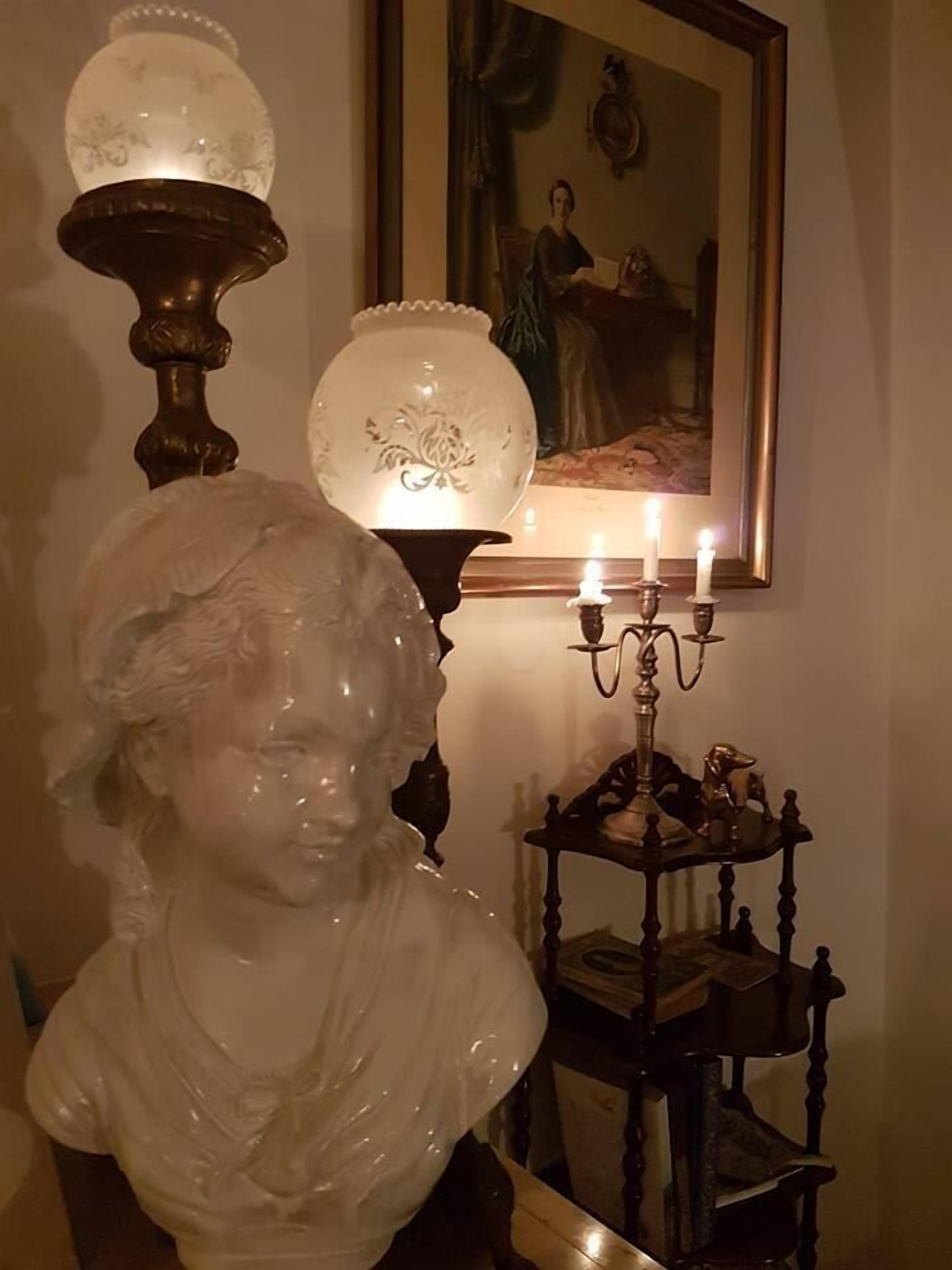 A bust sculpture, a wall-mounted lamp, and a candelabra with candles.