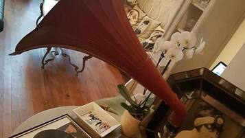 Una habitación con un tocadiscos antiguo, discos enmarcados y un objeto grande con forma de paraguas rojo.