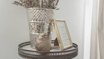 A decorative silver vase with dried flowers on a white pedestal table.