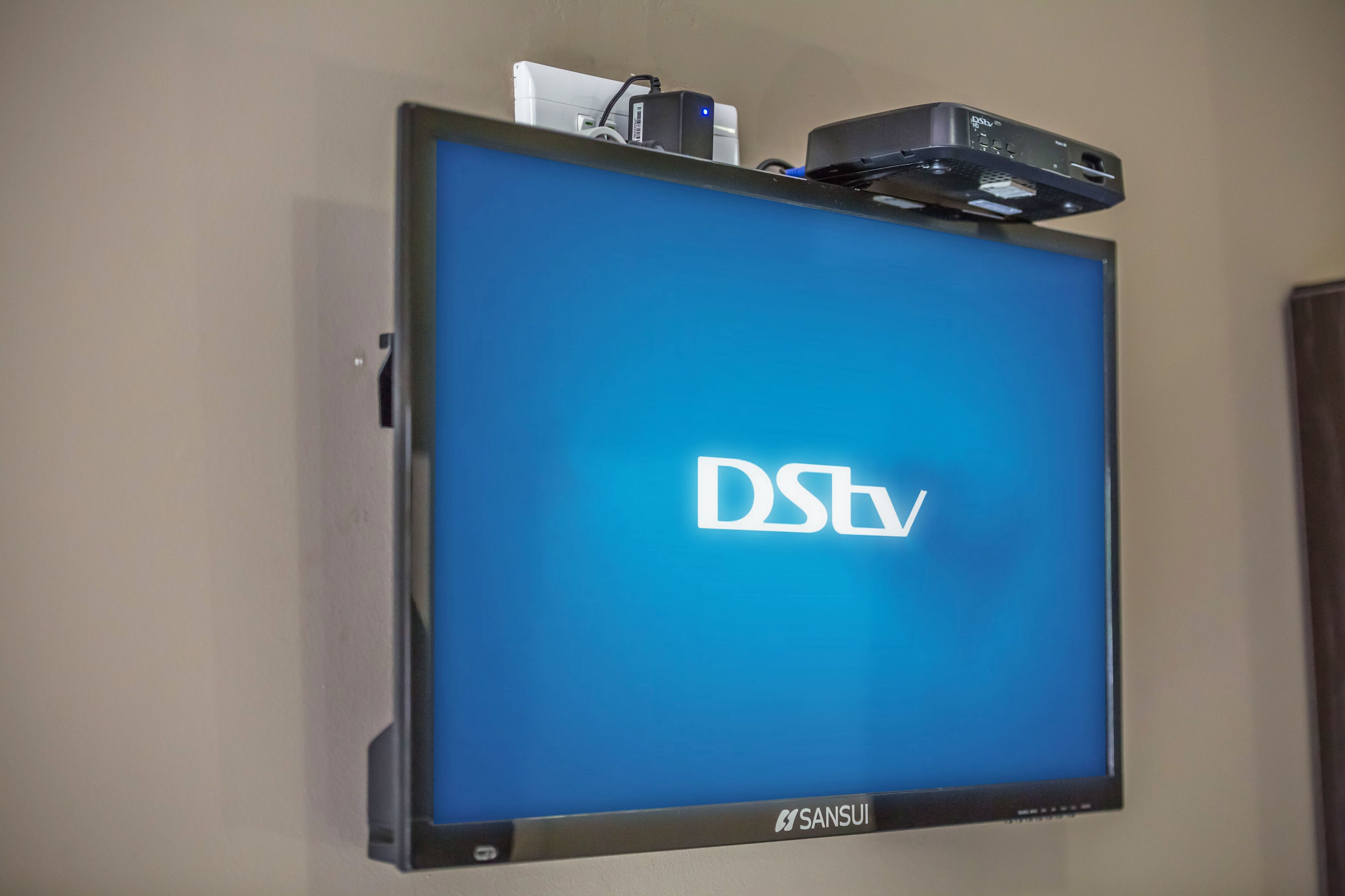 A flat-screen TV mounted on a wall displaying the DStv logo.
