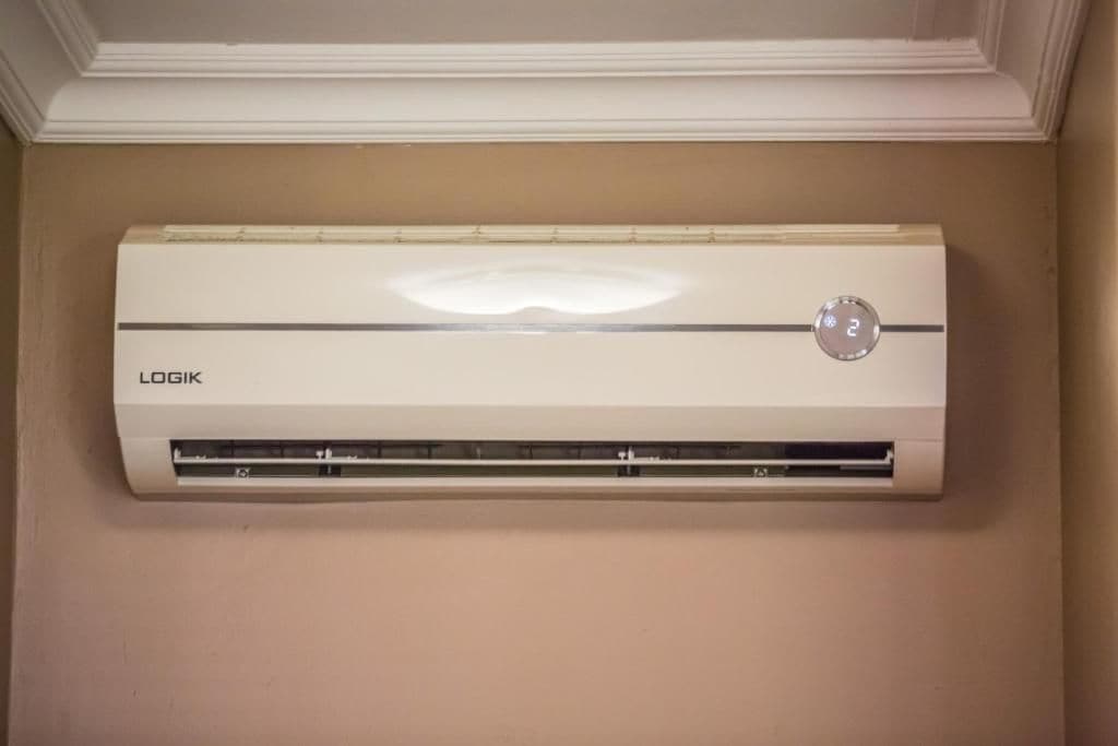 A white air conditioning unit mounted on a wall with a control panel displaying the number 2.
