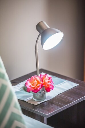 A bedside table with a lamp and a vase of flowers.
