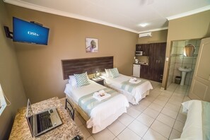 A hotel room with two beds, a TV, a laptop, a microwave, and a bathroom. - Beryl1 Guest House (Klerksdorp)