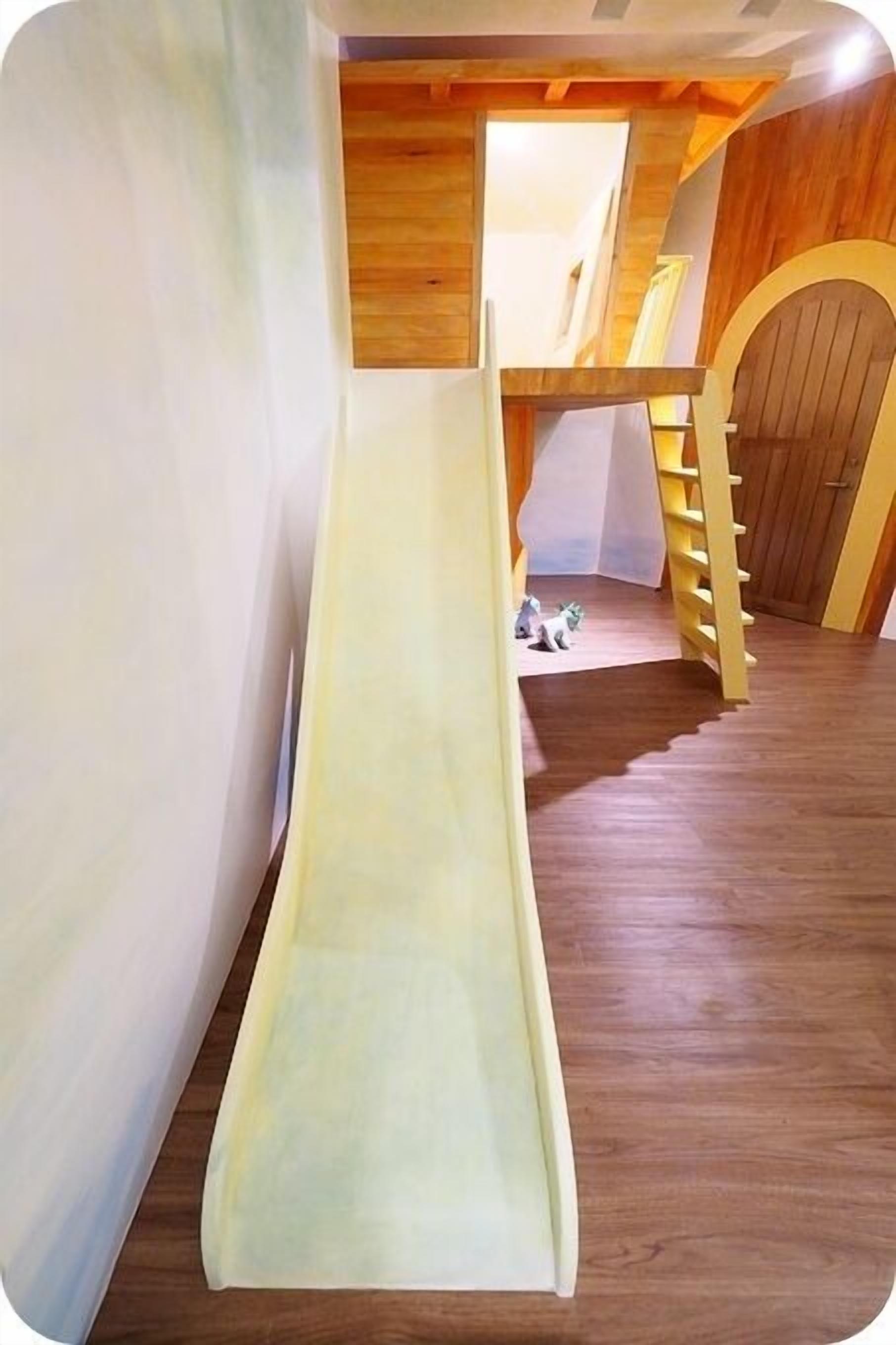 A children's play area with a slide, wooden walls, and a staircase.