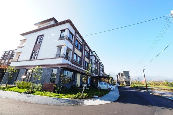 A modern multi-story residential building with balconies, a gated driveway, and a clear sky. - Cest Mignon (Dongshan)