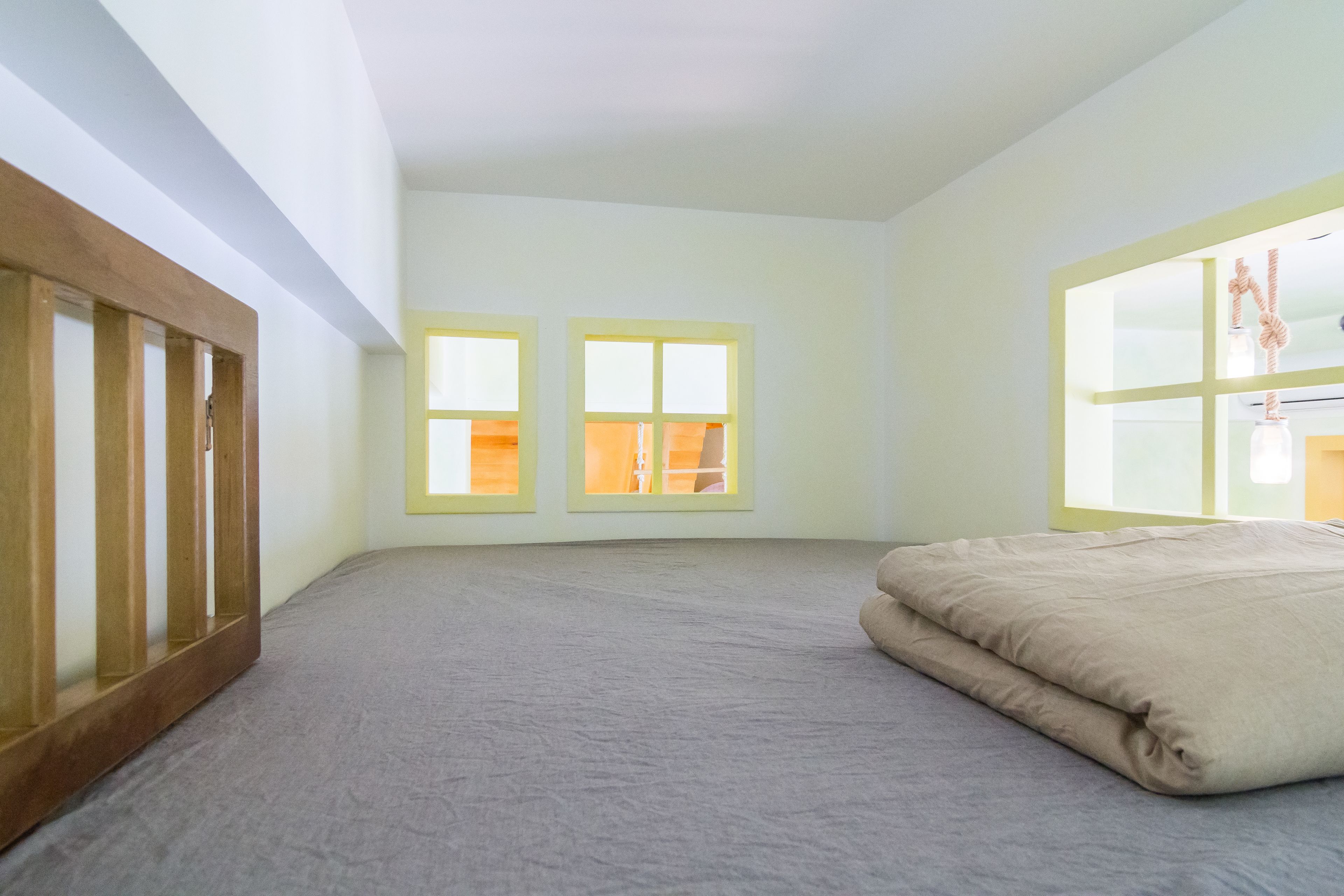 A bedroom with a bed, two windows, and a wooden headboard.
