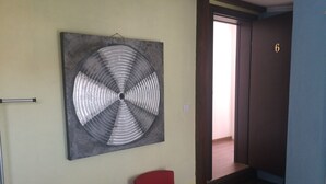 A room with a large abstract artwork on the wall, two red chairs, a small table with a basket, and a staircase leading to another room. - Montenegro central point (Podgorica)