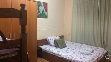 A bedroom with a wooden bed, a small bedside table, a wardrobe, and a painting on the wall.