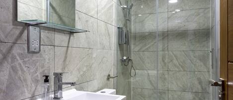 Ein modernes Badezimmer mit Duschkabine aus Glas, einem weißen Waschbecken und einer Toilette.