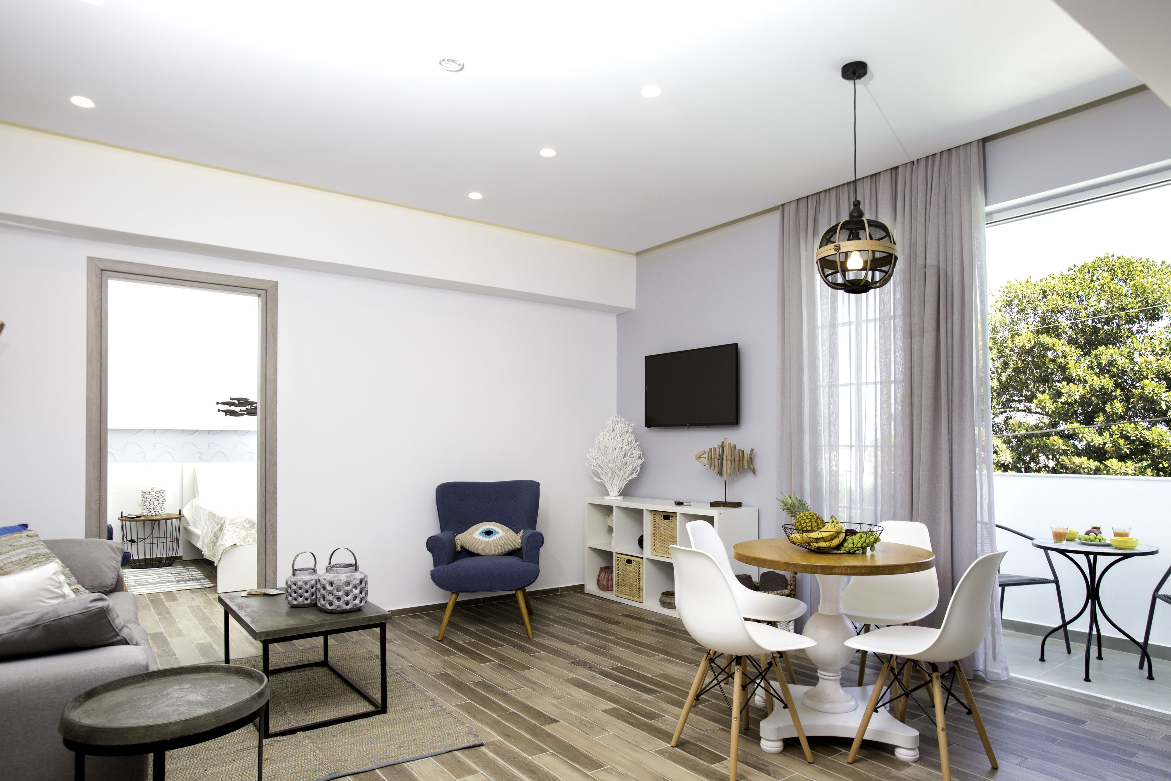 Una sala de estar moderna con un sofá, una mesa de comedor, sillas y un sillón azul.