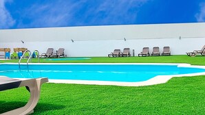 A swimming pool with multiple lounge chairs and a covered seating area. - HMB Fermentelos Hotels (Agueda)