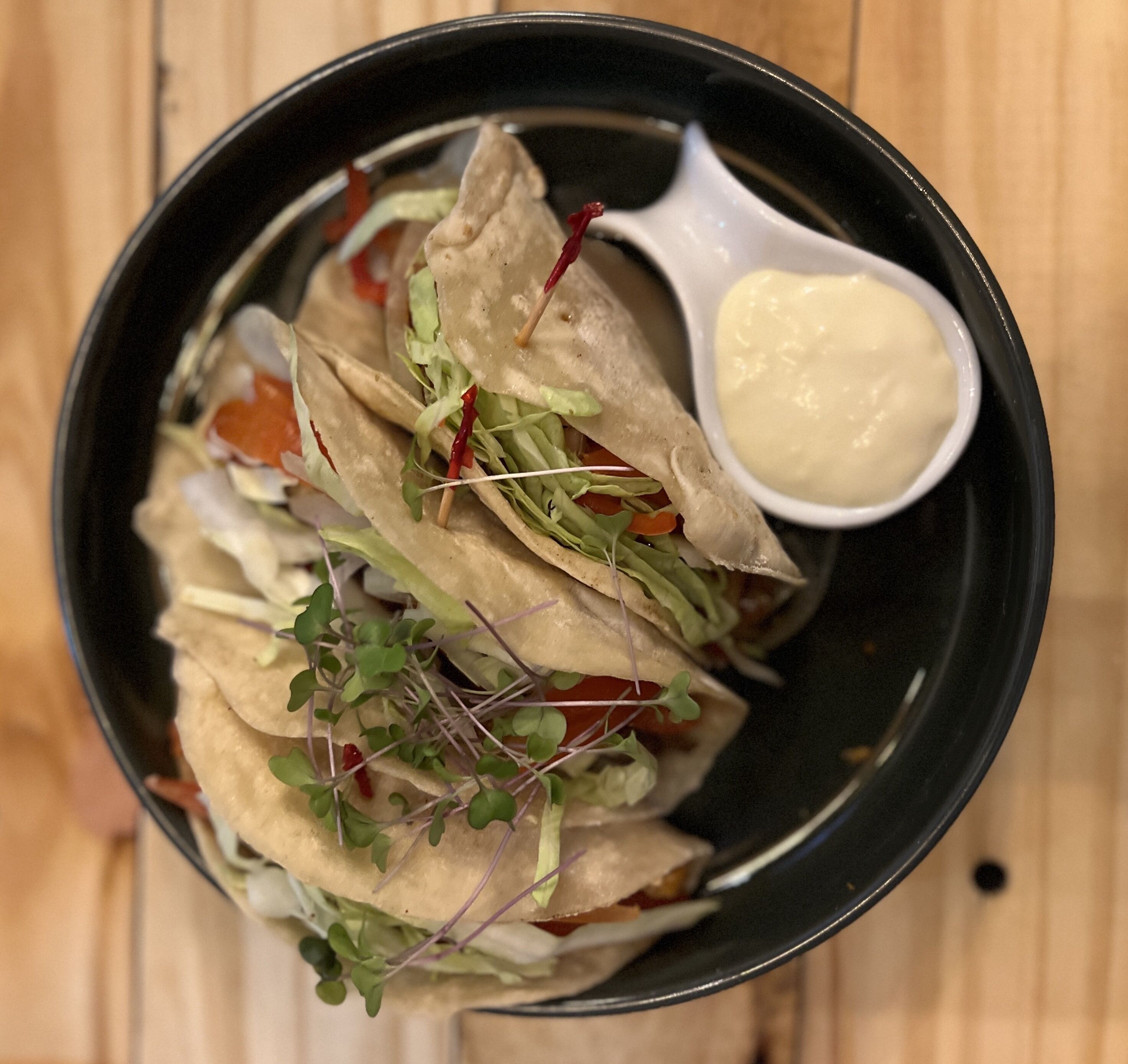 Un plato de tacos con salsa aparte.