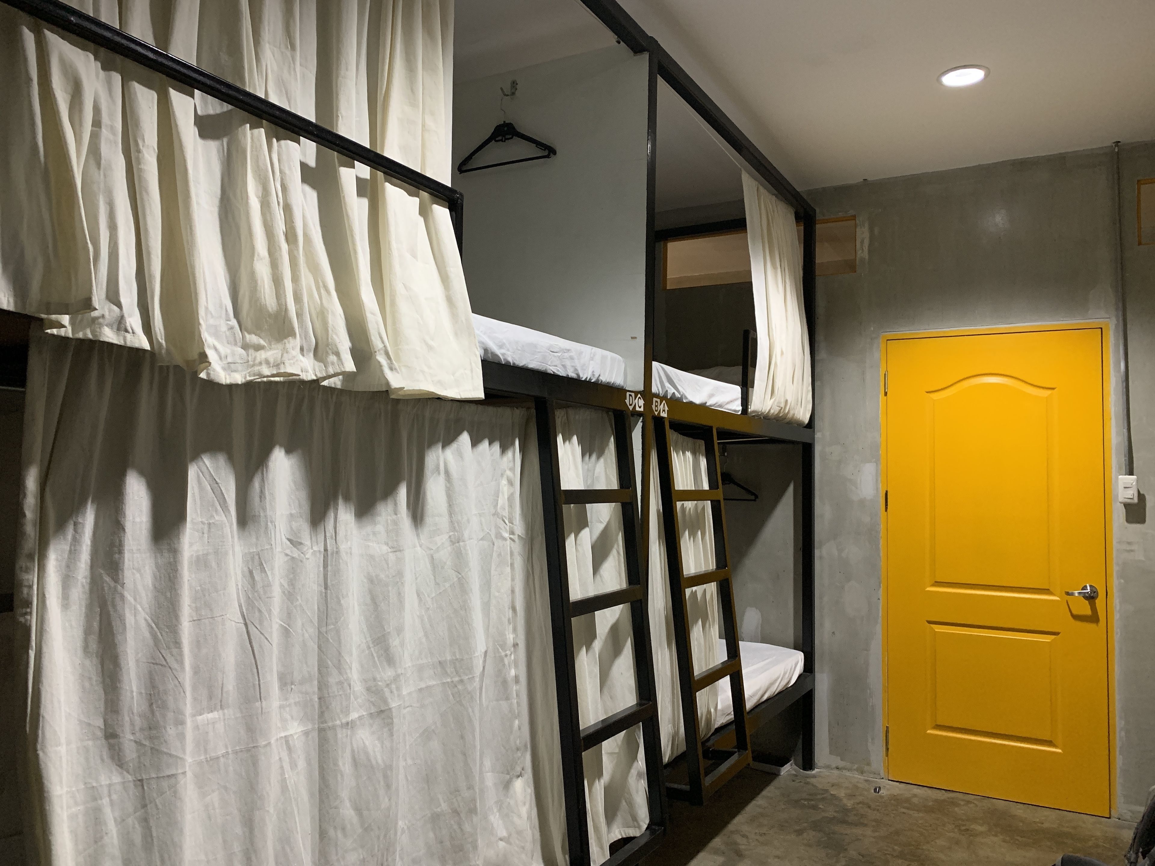 A bunk bed room with a yellow door and a white curtain.