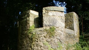 A stone castle ruin with an arched entrance, surrounded by greenery. - Schloss Egg (Bernried)