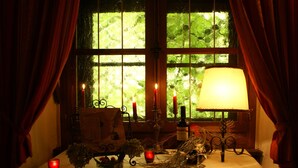 A table with candles, a lamp, and a window with curtains. - Schloss Egg (Bernried)