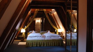 A room with a sloped ceiling, two beds with white linens, and lamps on nightstands. - Schloss Egg (Bernried)