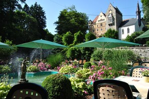 A courtyard with a fountain, outdoor seating, and a historic building in the background. - Schloss Egg (Bernried)