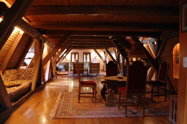 An attic room with wooden beams, a sofa, chairs, a table, and a rug. - Schloss Egg (Bernried)