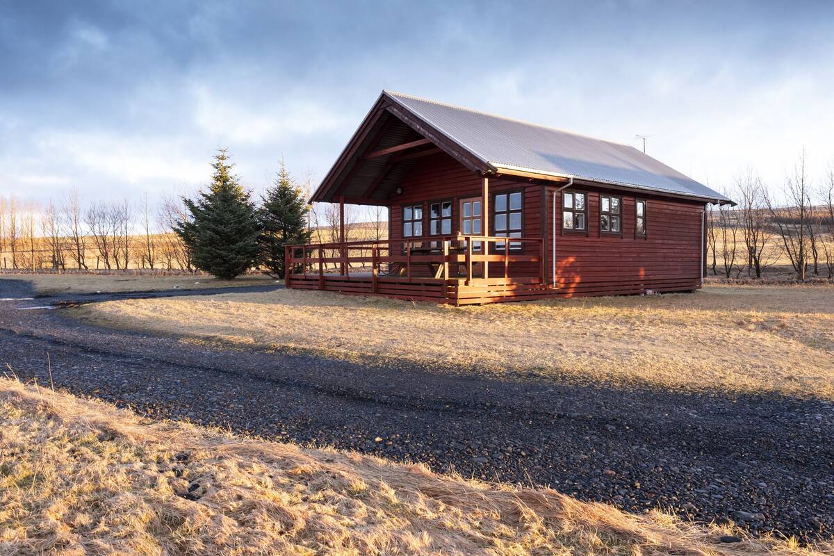 Une cabane en bois avec un toit en métal, une véranda et une allée gravillonnée.