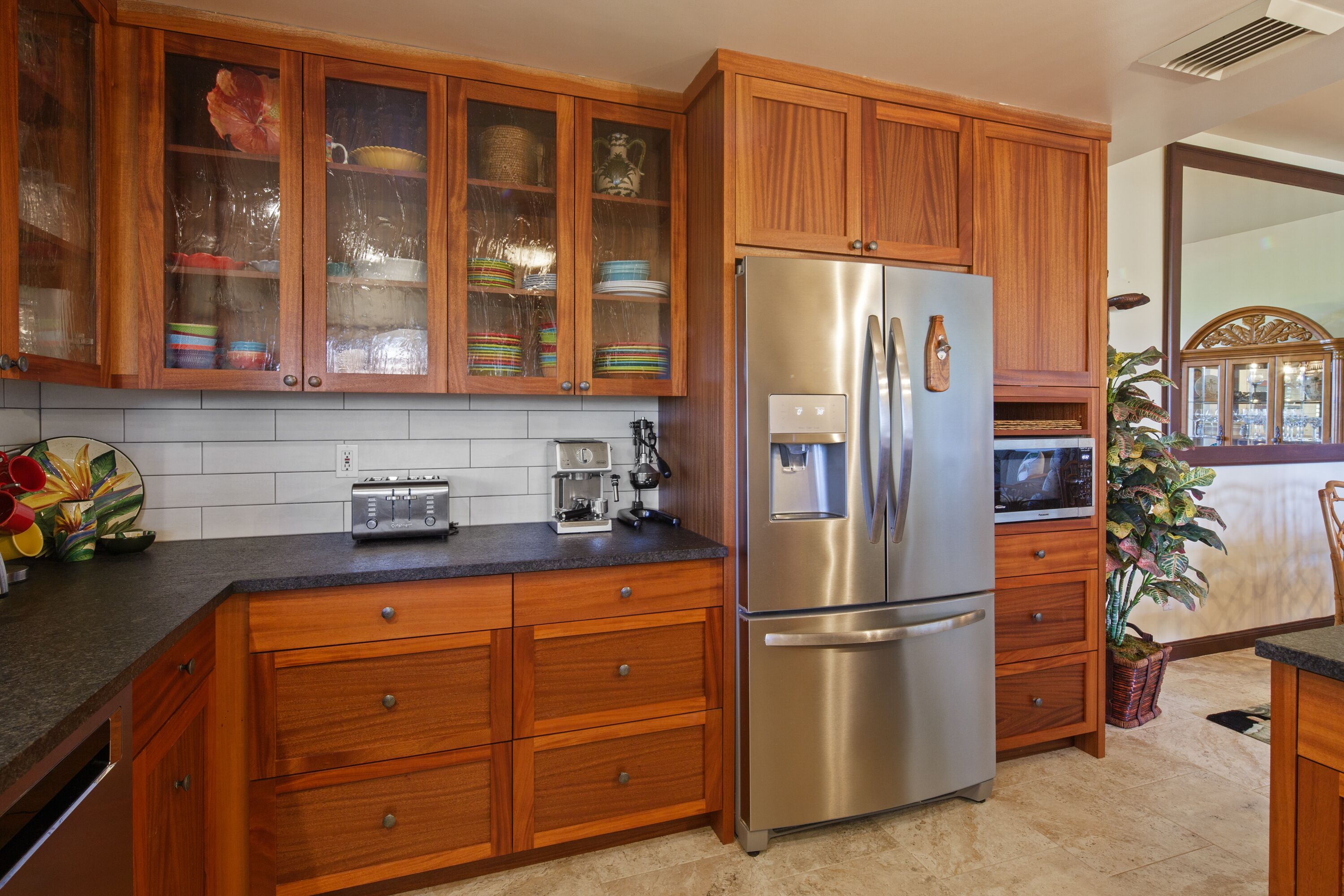 Una cocina con armarios de madera, un refrigerador de acero inoxidable, un microondas y un tostador.