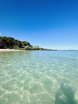 A clear beach with calm waters and a sandy shore.