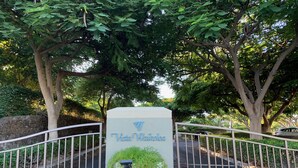A sign for Vista Waikoloa with a gated entrance, surrounded by lush greenery and trees.