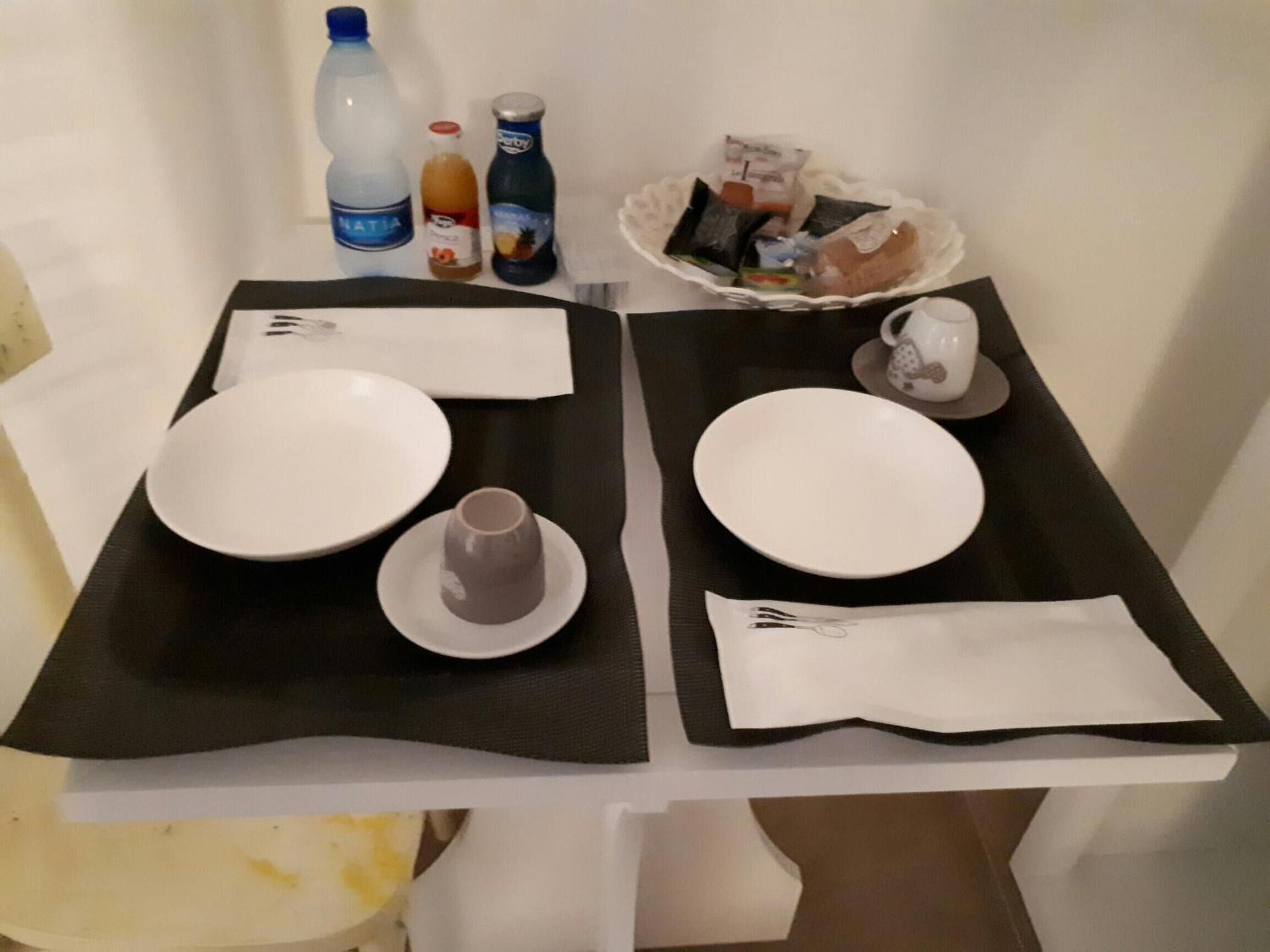 A neatly arranged dining table with two plates, cutlery, and a small cup.