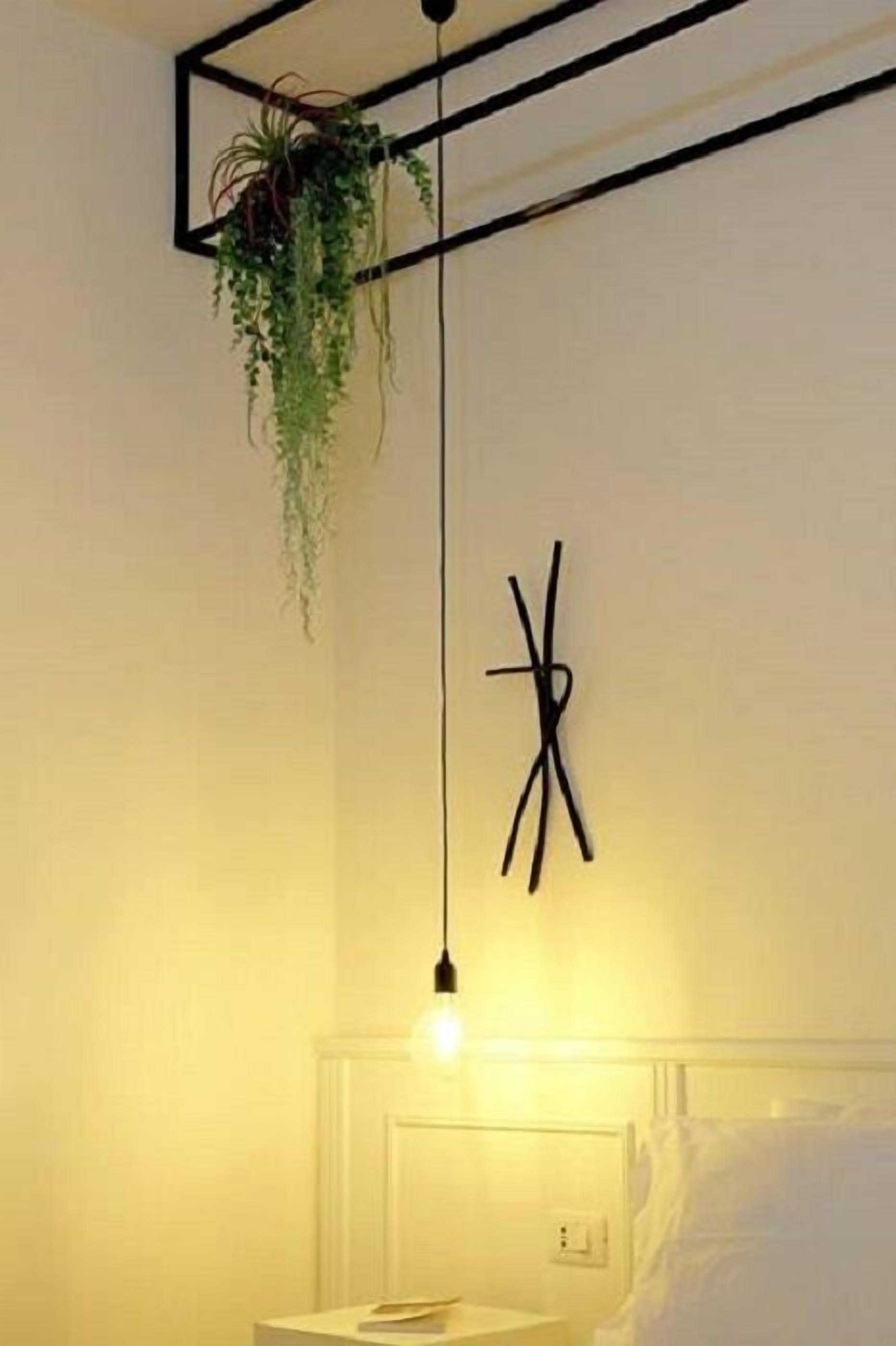 Ein Zimmer mit einer hängenden Pflanze, einer Nachttischlampe, einem Nachttisch und einem Bett.