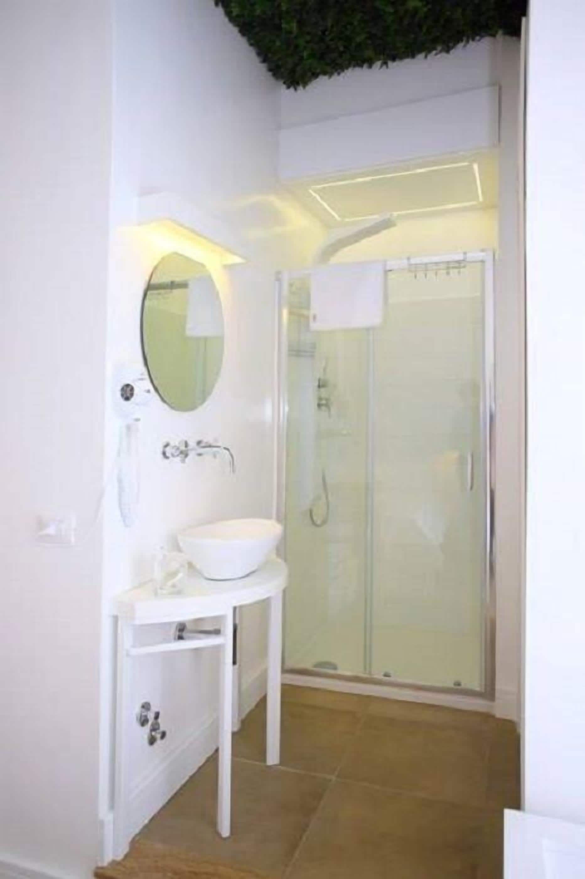 A modern bathroom with a white sink, mirror, and glass shower enclosure.