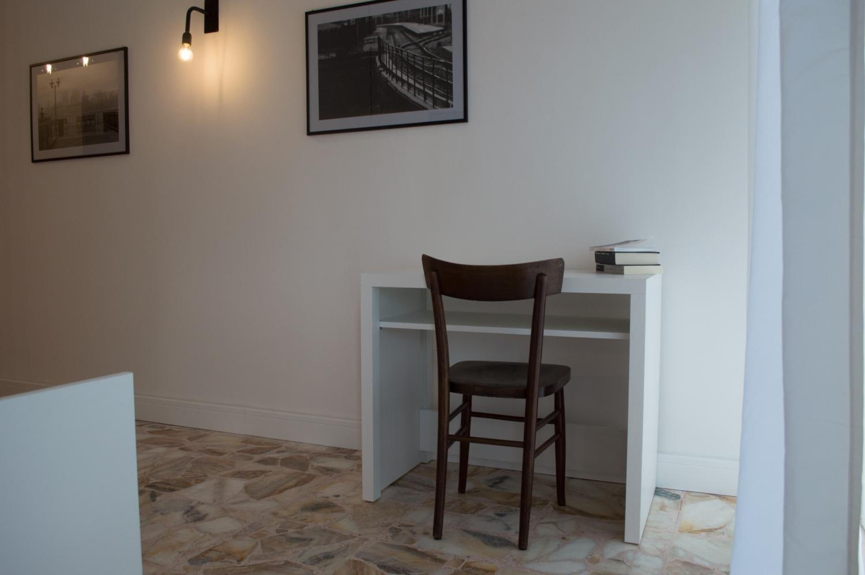Ein Zimmer mit Schreibtisch, Stuhl und zwei Bildern an der Wand.