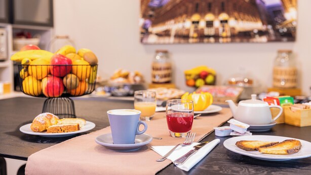 A breakfast table with a fruit bowl, coffee cup, juice, toast, and a teapot. - Martini Suite (Milan)