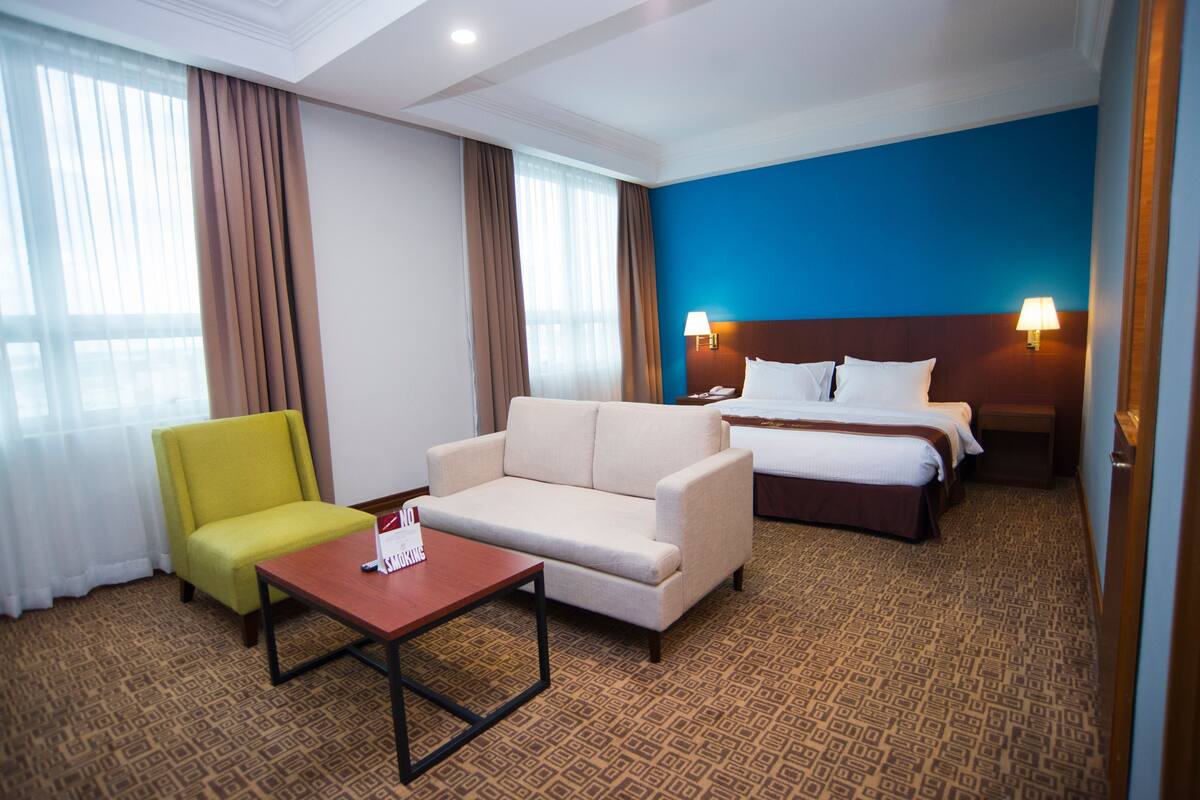 A hotel room with a bed, a sofa, a small table, and a chair.